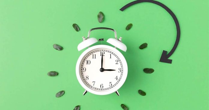 Ceas de perete pe fundal de primavara indicand schimbarea orei