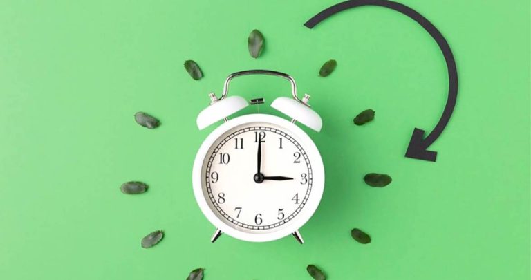Ceas de perete pe fundal de primavara indicand schimbarea orei
