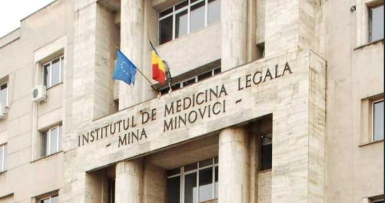 Un medic legist completând un formular oficial, o ștampilă și un dosar medical pe un birou