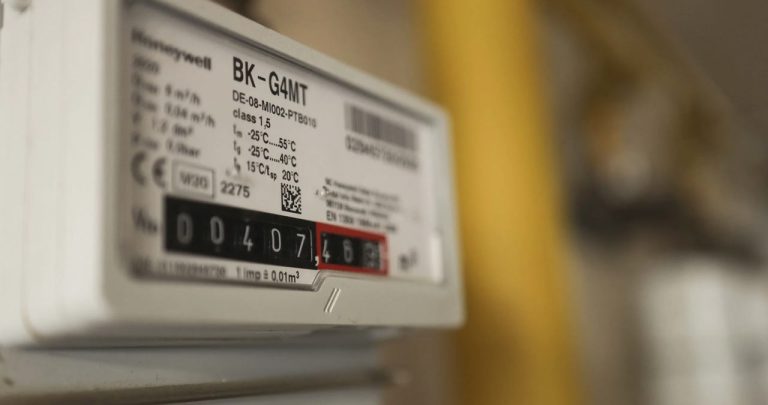 Un aviz galben de citire a contorului agățat de o poartă de metal încuiată a unei case rezidențiale