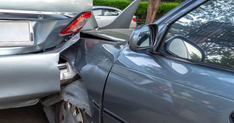 Doi șoferi stând lângă mașini avariate, unul explicând polițistului rutier că i-a expirat asigurarea RCA