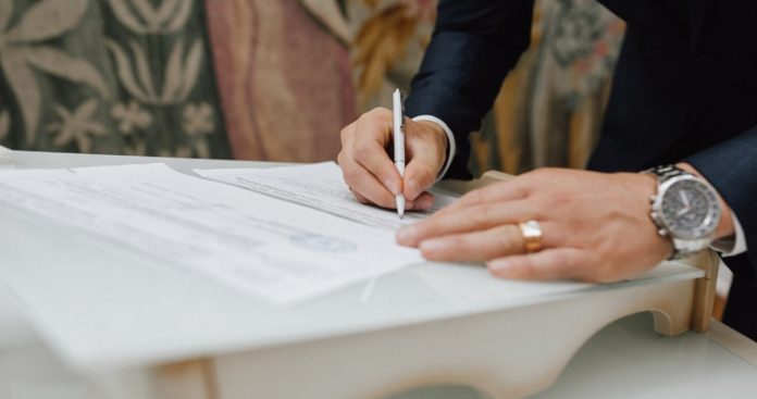 Acte Cununie Civila 2026 Starea Civila Analize Un cuplu fericit semnând certificatul de căsătorie în fața ofițerului de stare civilă având alături buletinele și dosarul medical