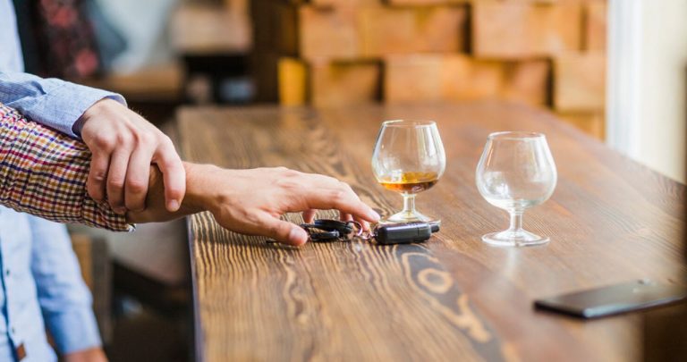 Un polițist rutier întinzând un aparat etilotest unui șofer oprit pe timp de noapte, ecranul aparatului afișând o valoare numerică roșie