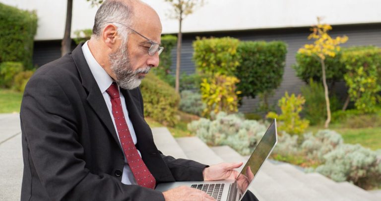 Un utilizator fericit completând online cererea pentru certificatul fiscal pe un laptop având cheile mașinii alături