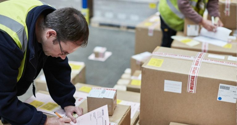 Un morman de colete poștale internaționale pe o bandă de sortare, așteptând inspecția vamală