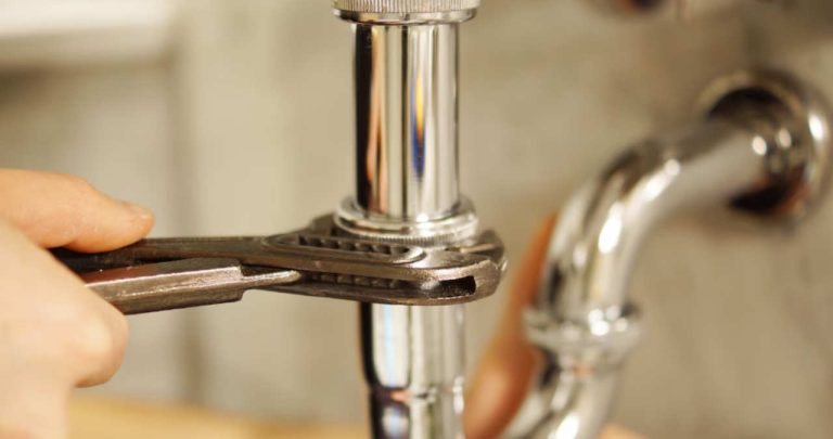 Un instalator demontând un contor general de apă din subsolul unui bloc în vederea trimiterii acestuia la verificarea metrologică oficială