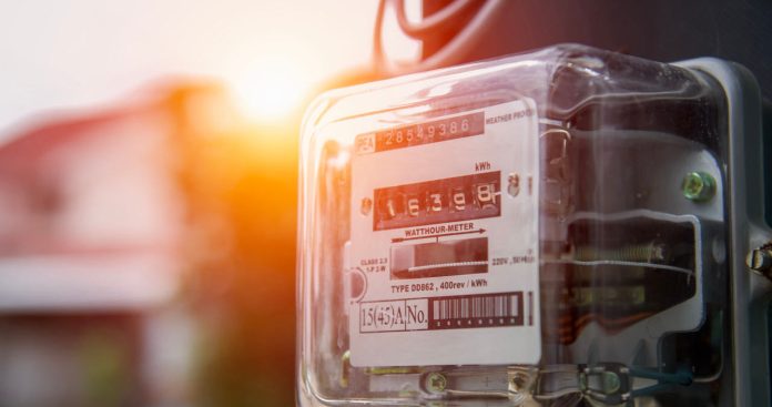 Un specialist dintr-un laborator metrologic testând un contor electric conectat la un aparat de măsurare a impulsurilor