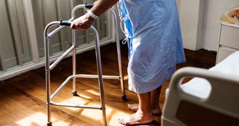 Un pacient zâmbind alături de un medic specialist în timp ce primește un aparat auditiv nou decontat parțial de stat