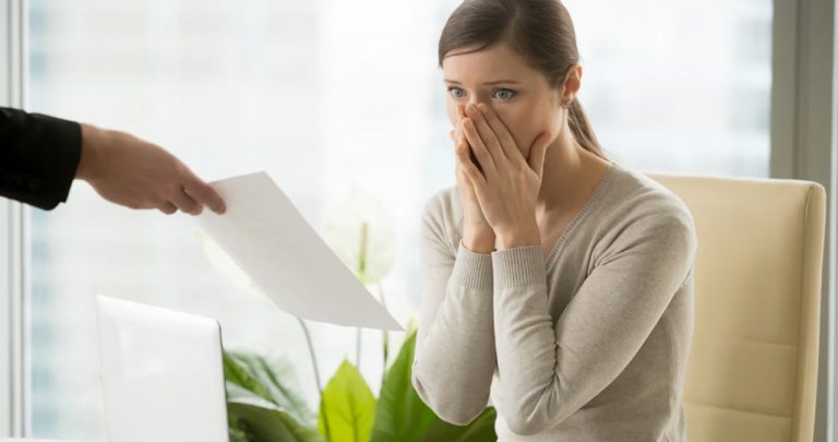 Un angajat semnând o notificare de încetare a contractului de muncă la un birou și strângându-și lucrurile