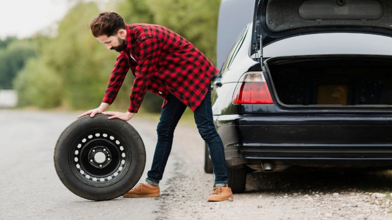 Roata auto cu janta indoita si anvelopa distrusa langa o groapa adanca in asfalt