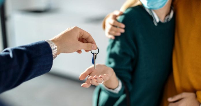 Un proprietar de apartament ținând în mână un contract de credit și un acord oficial de la Ministerul Finanțelor, discutând la masă cu un ofițer bancar