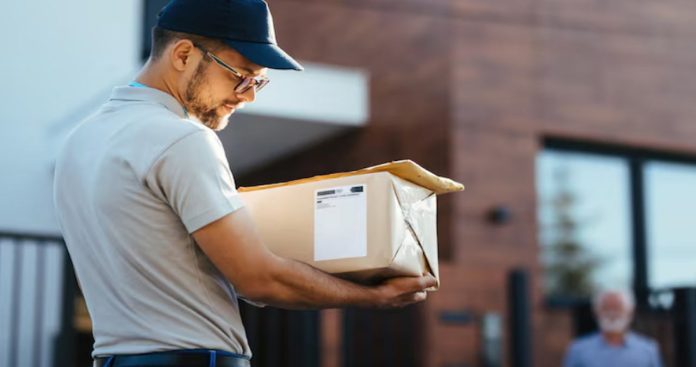 Deschidere Colet la Livrare Curier Verificare 2026 Un client fericit inspectând vizual un produs scos dintr-o cutie de carton, asistat de un curier cu un scanner în mână