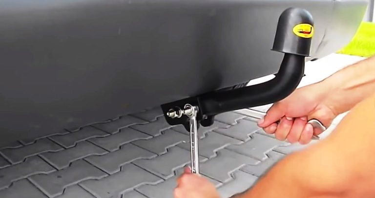 Mecanic auto care montează un cârlig de remorcare pe șasiul unei mașini într-un service autorizat RAR