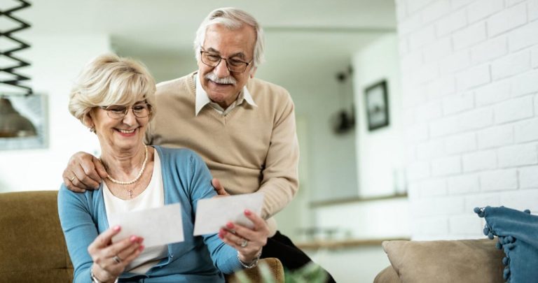 Un viitor pensionar privind un fluturaș de salariu din străinătate și un dosar cu acte lângă un steag al Uniunii Europene