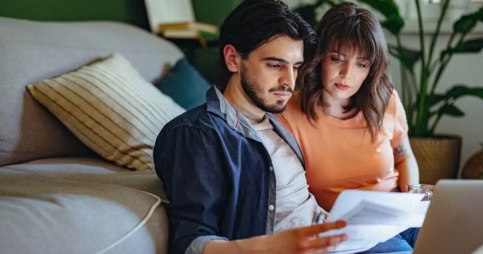 Un client completând cu un pix un formular de restituire sume energie, având alături un laptop deschis pe o factură cu sold creditor