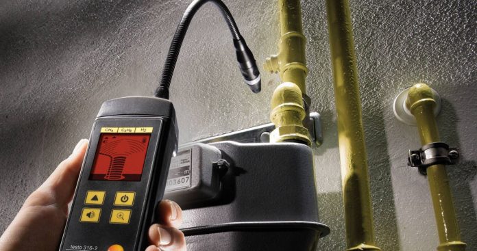 Instalator autorizat verificând presiunea la o țeavă de gaze folosind un aparat electronic de măsură