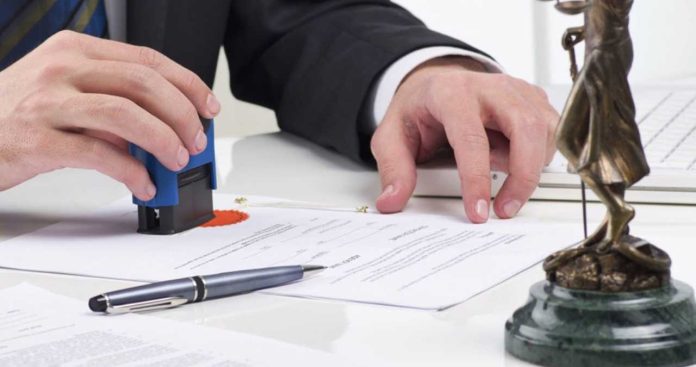 Un executor judecătoresc redactând și ștampilând o somație de plată oficială pentru recuperarea unui debit restant în anul 2026
