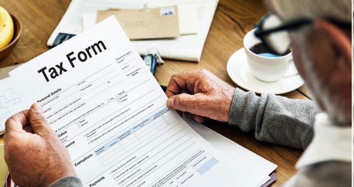 Un curier livrând o cutie de carton unui client care verifică o factură cu taxe vamale pe telefon