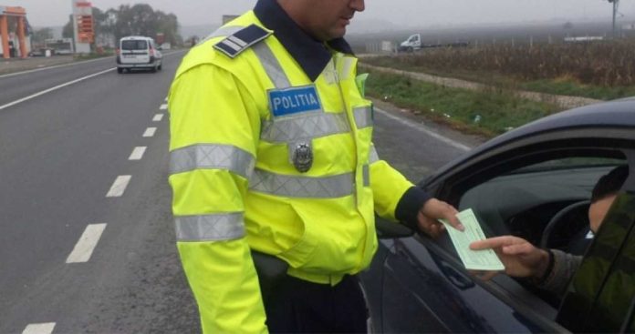 Un șofer fotografiind un indicator rutier Cedează Trecerea ascuns complet după crengile unui copac pentru a-l folosi ca probă în instanță