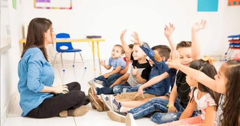 Copil fericit oferind un buchet de flori doamnei educatoare în sala de grupă, reprezentând un gest de mulțumire